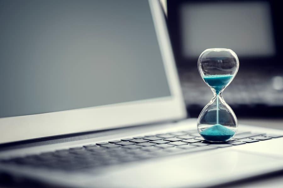 An hourglass showing the progression of time on a laptop keyboard